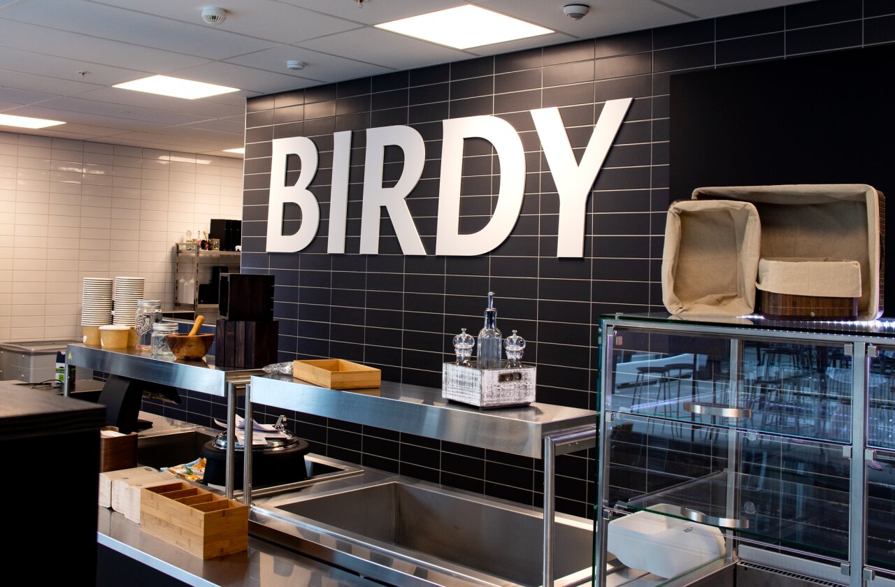 Birdy kantina med stor hvit logo på svart vegg.