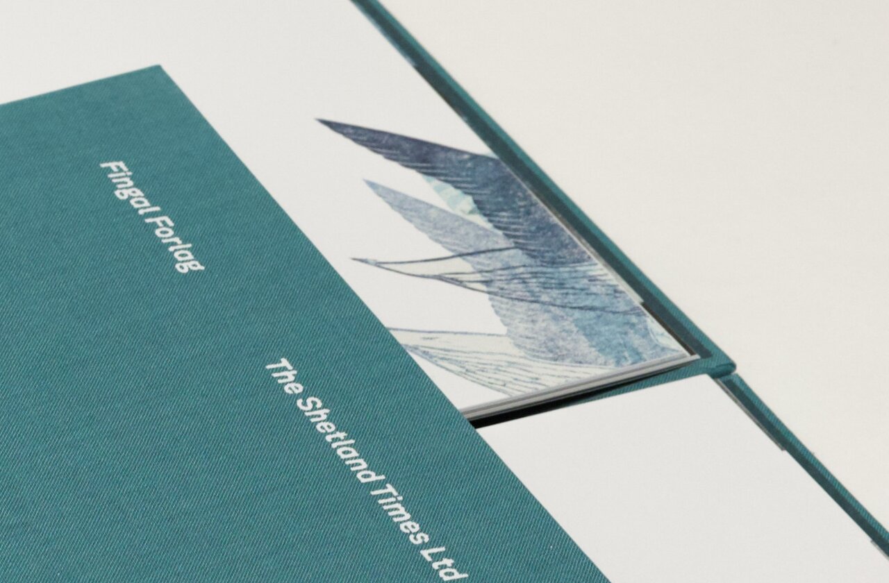 Detaljbilde som viser vinger nederst på en bok side. Deler av bokcover vises i forgrunnen.