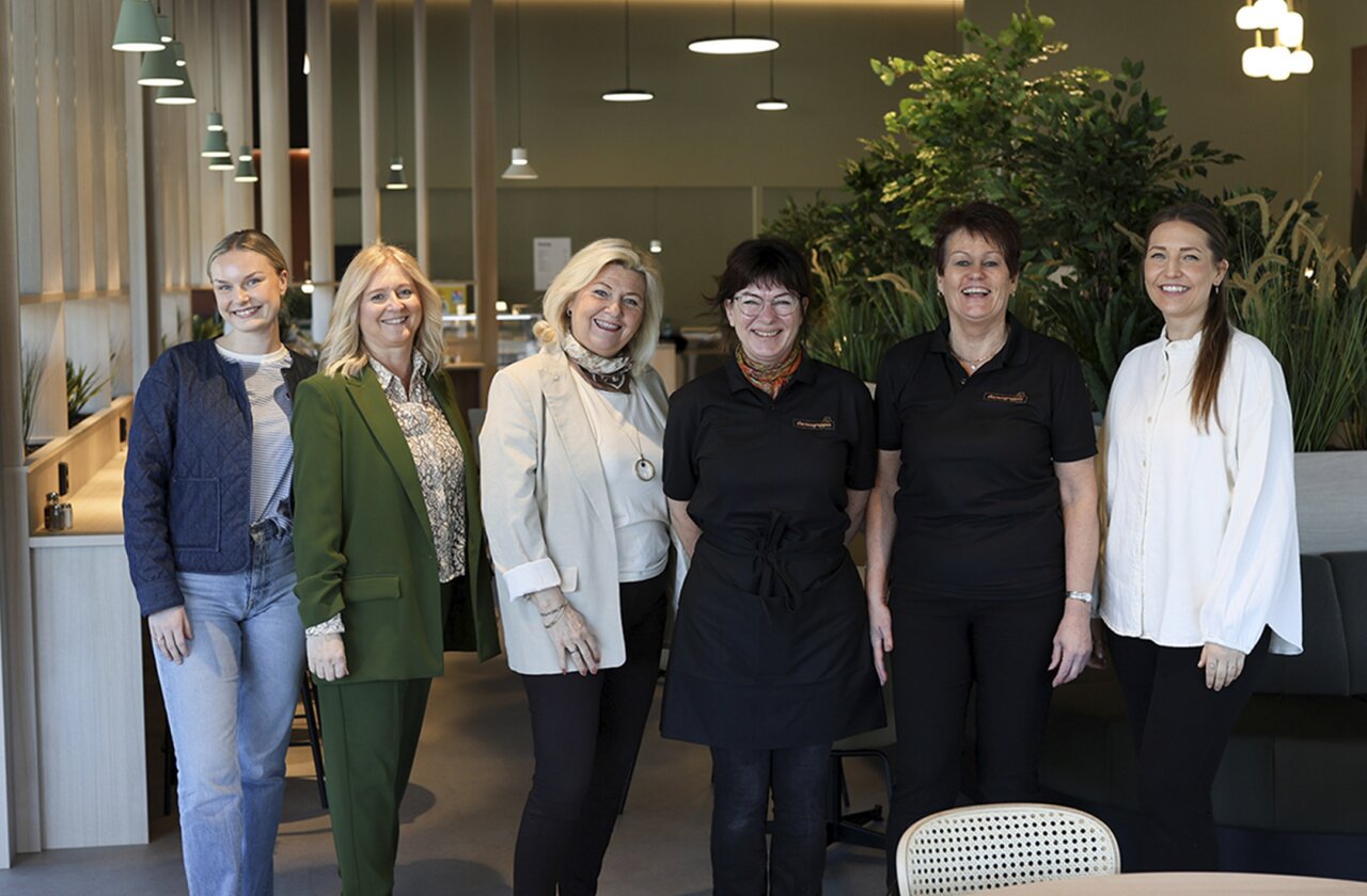 Smilende gruppe mennesker på linje.