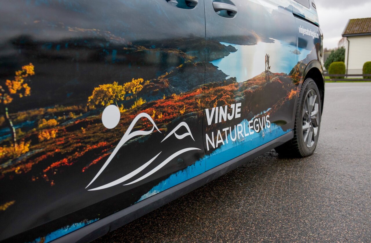 Detaljer i bunn av bil, med logo og naturbilde.