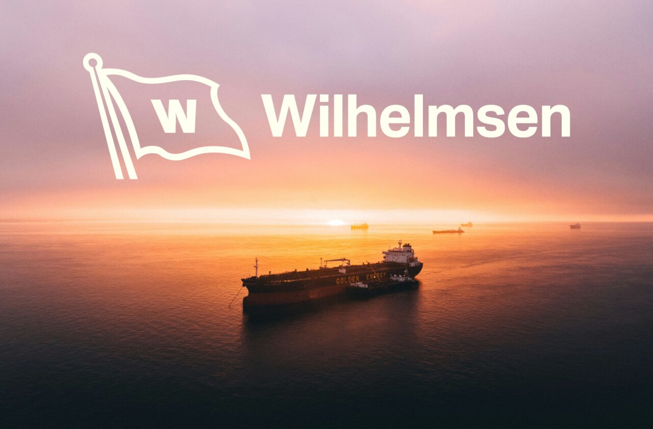 Hvit Wilhelmsen logo på bakgrunn med båt i solnegang.